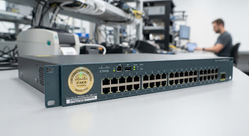 Refurbished Cisco Catalyst 3850 switch showing authentic gold factory certified seal and clean ports inspected under testing lights